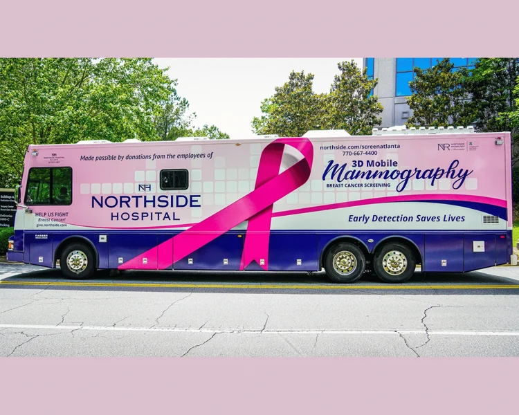 A Northside Hospital 3D mobile mammography bus with a large pink ribbon and the slogan “Early Detection Saves Lives” is parked on a street.