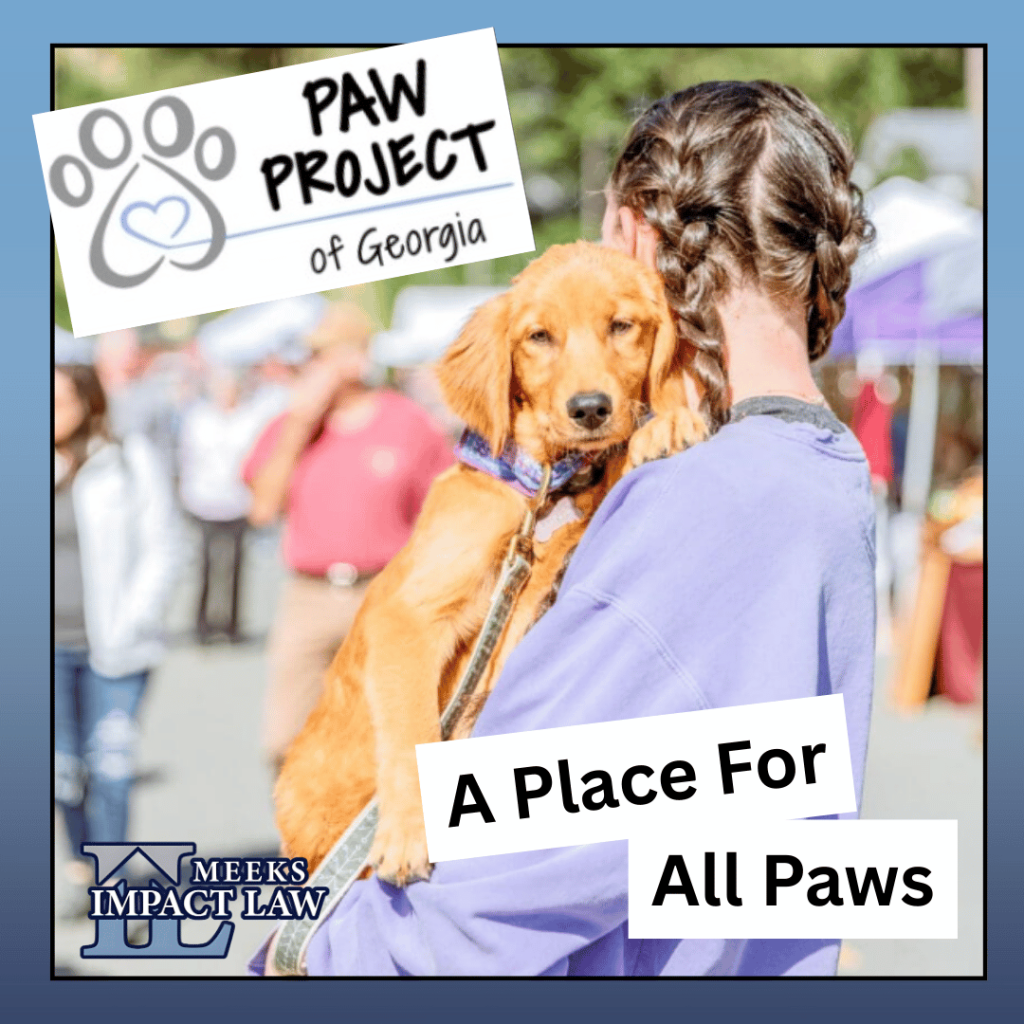 Person in a lavender sweatshirt holding a golden dog at an outdoor event. Text reads: PAW Project of Georgia, A Place For All Paws, and Meeks Impact Law.