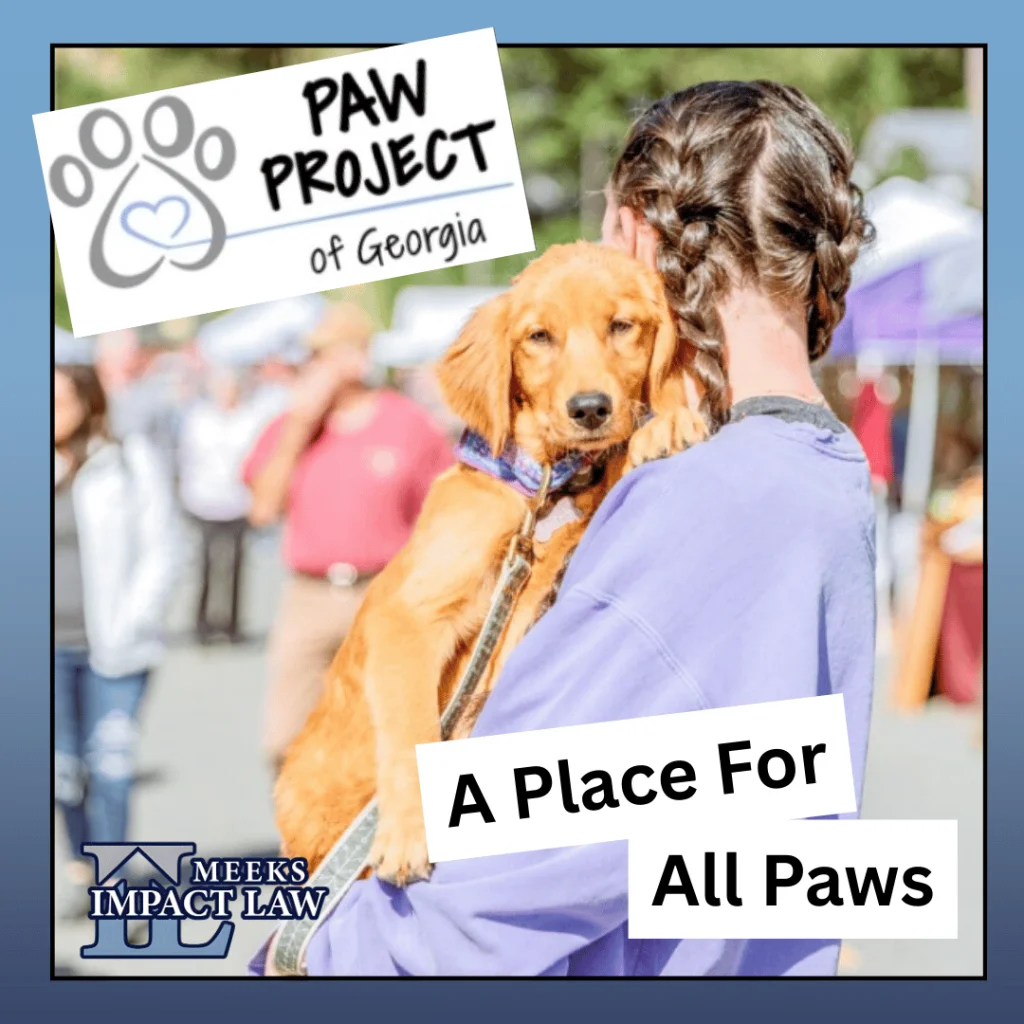 Person in a lavender sweatshirt holding a golden dog at an outdoor event. Text reads: PAW Project of Georgia, A Place For All Paws, and Meeks Impact Law.