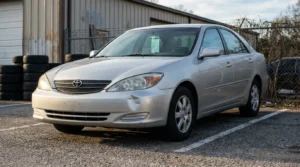 Toyota Camry sedan with visible front bumper damage parked in lot